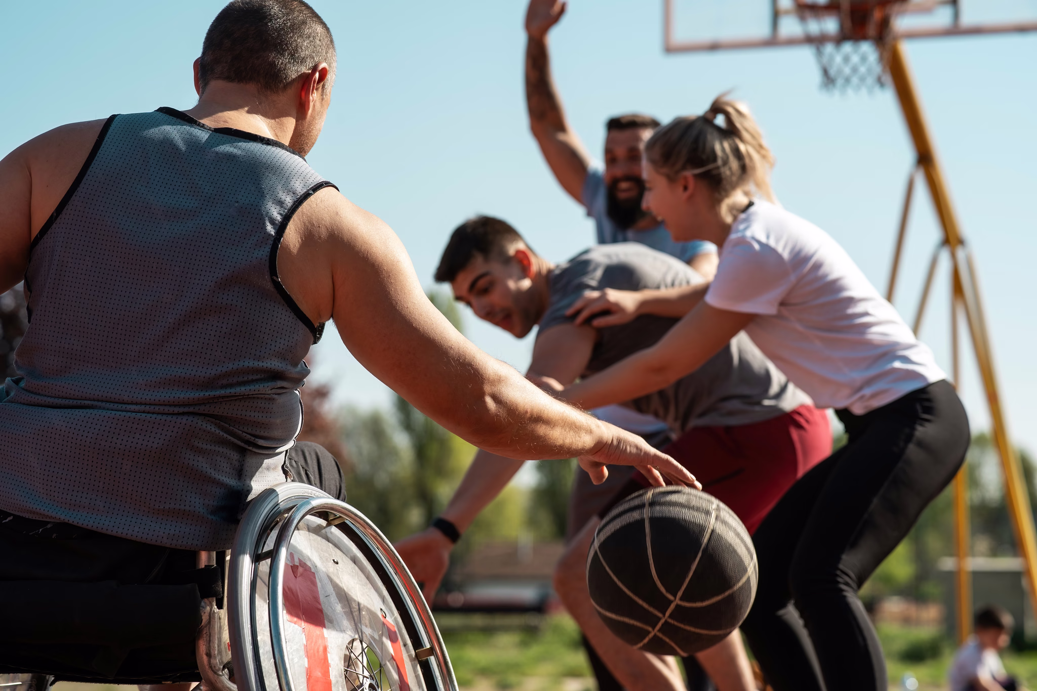 Adults playing basketball together outdoors